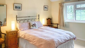 A neatly made bed with a white and pink bedspread, two bedside tables with lamps, a wooden chair, and a window with curtains. - 20 steps to entrance with handrail. (Burnsall near Grassington)