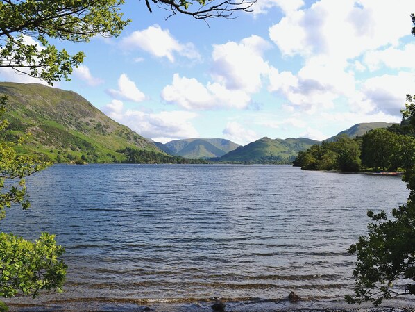 A lake surrounded by hills with trees and a clear sky.