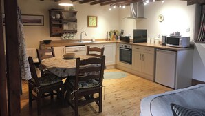 Una cocina compacta con armarios de madera, una mesa de comedor con sillas y un microondas.