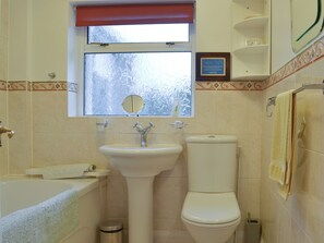 Une salle de bain avec un lavabo, des toilettes et une fenêtre située au-dessus du lavabo.
