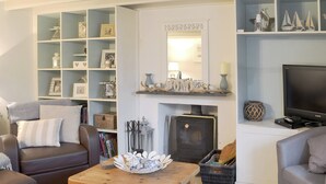 A cozy living room with a fireplace, a television, and a bookshelf filled with various items. - 3 bedroom accommodation in Helstone, near Camelford (Helstone, near Camelford)