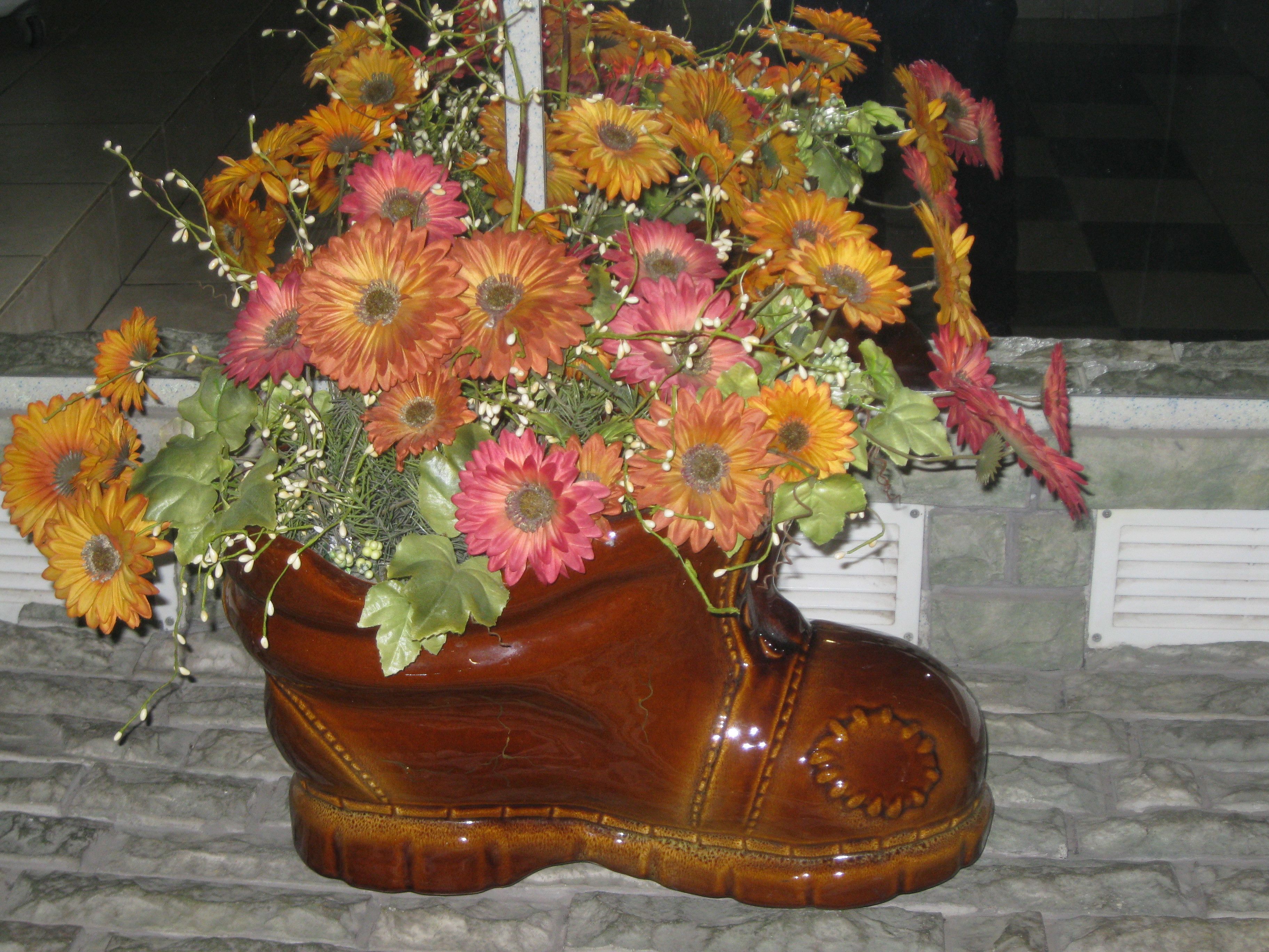 A decorative flower arrangement in a ceramic boot-shaped vase.