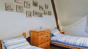 A room with two single beds, a wooden dresser, a nightstand with a lamp, and a wall with framed pictures. - 2 bedroom accommodation in Aughton, near Marlborough (Aughton, near Marlborough)