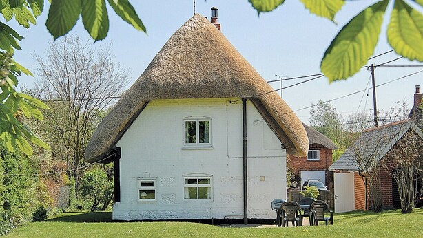 A white house with a thatched roof, surrounded by greenery and a small garden. - 2 bedroom accommodation in Aughton, near Marlborough (Aughton, near Marlborough)