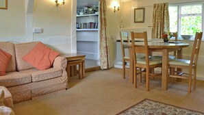 A cozy living room with a sofa, a dining table with chairs, a bookshelf, and a window with curtains. - 2 bedroom accommodation in Aughton, near Marlborough (Aughton, near Marlborough)