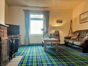 Un salon comprenant un téléviseur, un canapé, une table basse et un tapis à motifs.