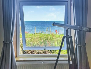 A telescope on a tripod outside a window with a view of the sea. - Delightful cottage overlooking Luce Bay, with open fire and enclosed garden. (Drummore, near Stranraer)