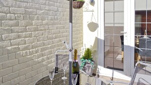 Une terrasse avec une table en verre, des verres à vin et une bouteille de champagne.