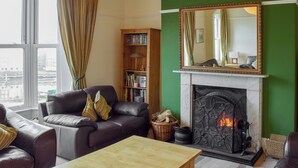 Una sala de estar con chimenea, sofás de cuero, una mesa de centro de madera y una estantería.