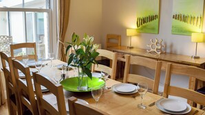 Un comedor con mobiliario de madera, un plato verde y un jarrón con flores.
