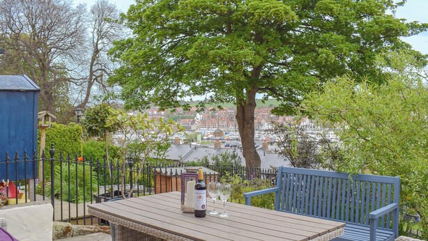 Un área de estar al aire libre con una mesa, sillas y una botella de vino.