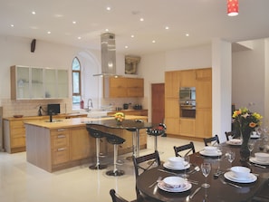 A modern kitchen with a central island, bar stools, and a dining table set for four.