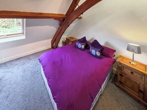 A bedroom with a bed, purple bedding, a nightstand, a lamp, and a window. - St Albans Church - 28165 (Treherbert, near Treorchy)