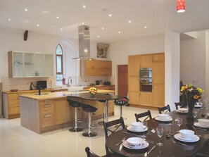 A modern kitchen with a central island, bar stools, and a dining table set for four. - St Albans Church - 28165 (Treherbert, near Treorchy)