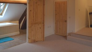A room with a skylight, wooden doors, a small window, and a staircase.