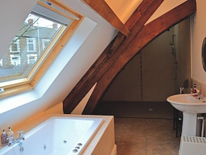 A bathroom with a skylight, a bathtub, a shower, and a sink.