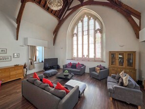 A spacious living room with wooden beams, a large arched window, and modern furniture. - St Albans Church - 28165 (Treherbert, near Treorchy)