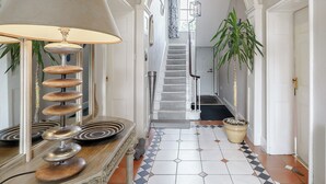 A hallway with a spiral lamp, a staircase, and a tiled floor.