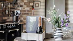 A kitchen counter with a wine bottle, a framed certificate, and a striped vase with flowers.