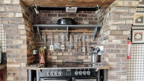 A kitchen with a brick wall, a stove, and hanging utensils.