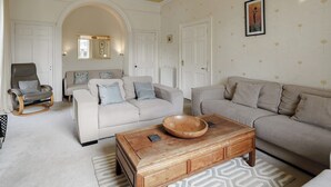 A living room with two sofas, a wooden coffee table, a chair, and a chandelier.