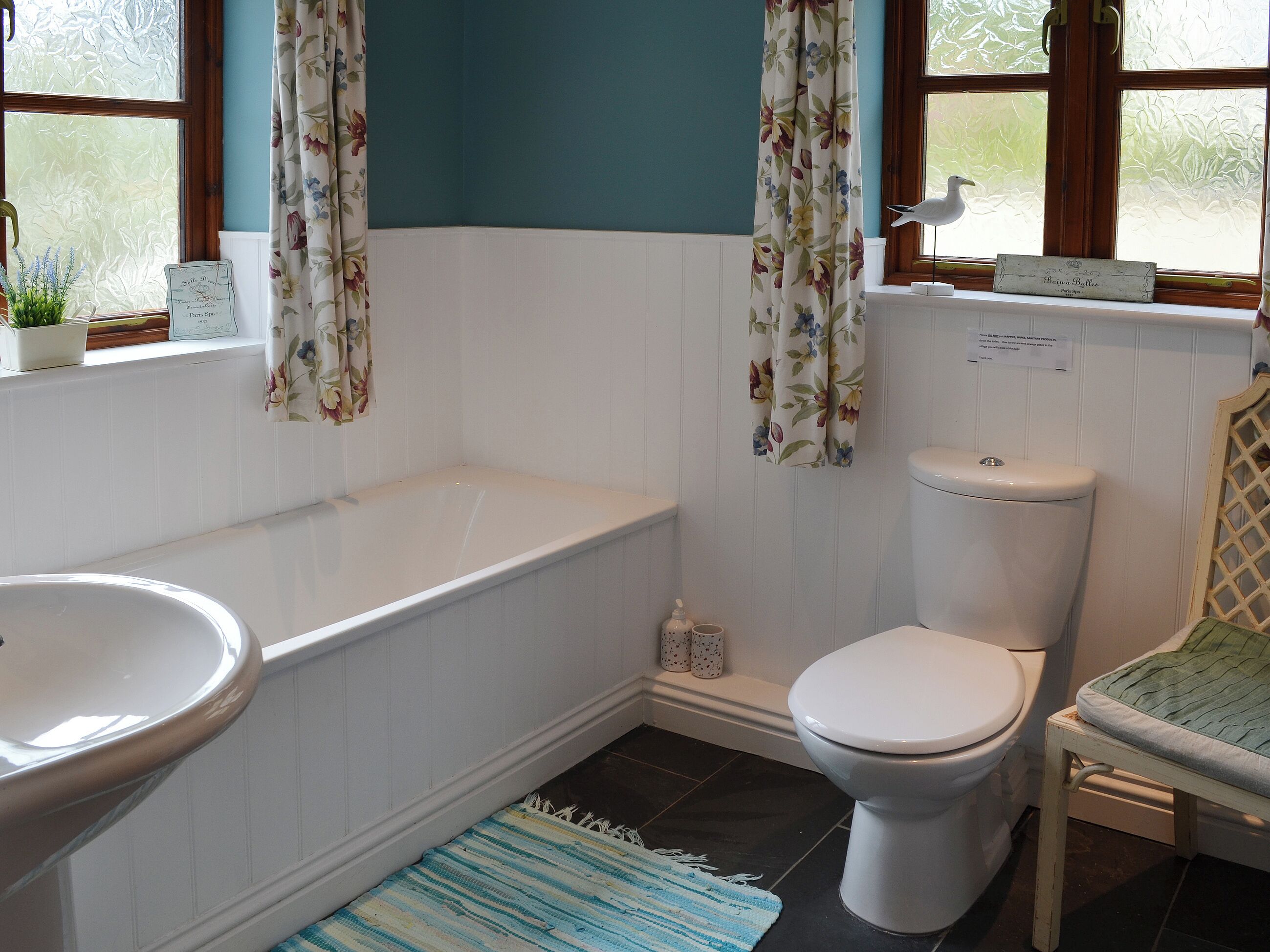 A bathroom with a bathtub, toilet, and a window with curtains.