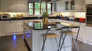 Une cuisine moderne avec des meubles blancs, un îlot central doté de tabourets, un four à micro-ondes et une grande fenêtre.