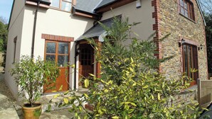 Une maison à deux étages avec une façade en pierre, une porte en bois et un petit porche.