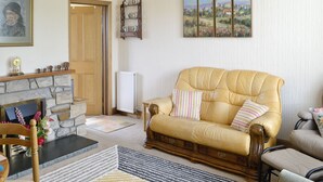 A cozy living room with a stone fireplace, a yellow leather sofa, and a painting of a landscape.