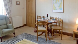 A dining area with a wooden table set for four, a chair, a radiator, a door, and a framed map on the wall.