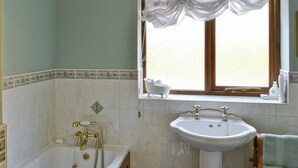 Een badkamer met een bad, een wastafel en een raam met gordijnen.