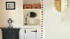 Ein Zimmer mit Kamin, Regalen mit Körben, einem gerahmten Bild, einem Spiegel und einer dekorativen Herzgirlande.