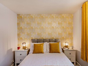 A neatly arranged bedroom with a bed, two bedside tables, and a nightstand. - Strawberries And Cream (Bowness on Windermere)
