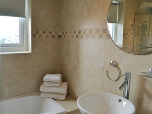 A bathroom with a bathtub, a sink, and a mirror. - Strawberries And Cream (Bowness on Windermere)