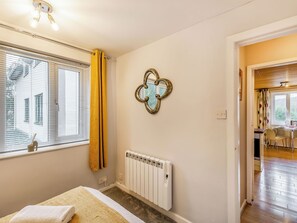 A bedroom with a bed, a radiator, a window with curtains, and a view of the outside. - Strawberries And Cream (Bowness on Windermere)