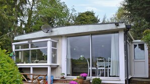 A house with large windows, a satellite dish, and a small porch area with potted plants. - 3 bedroom accommodation in Easthope, near Much Wenlock (Easthope, near Much Wenlock)