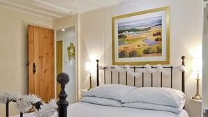 A bedroom with a bed, a wooden door, a framed painting, and a nightstand with a lamp. - 3 bedroom accommodation in Easthope, near Much Wenlock (Easthope, near Much Wenlock)