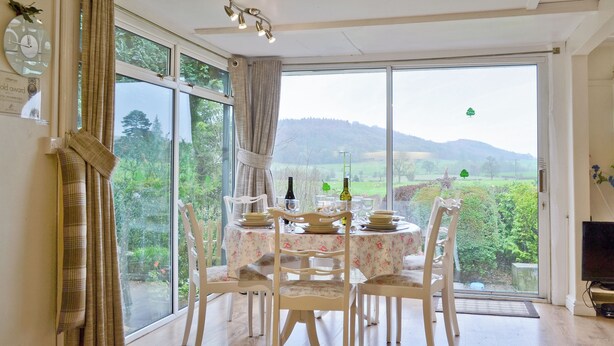 A dining area with a table set for four, large windows, and a view of the countryside. - 3 bedroom accommodation in Easthope, near Much Wenlock (Easthope, near Much Wenlock)
