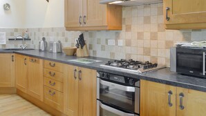A modern kitchen with wooden cabinets, a gas stove, an oven, a microwave, and a sink.