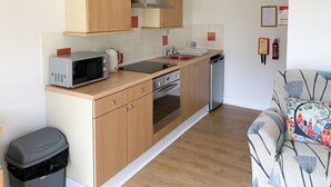 Una cocina compacta con armarios de madera, microondas, hervidor y lavavajillas.
