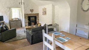 Una sala acogedora con chimenea, una mesa de comedor con sillas, un sofá y una televisión.