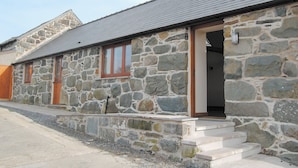 A stone building with a sloped roof, wooden doors, and a small porch.