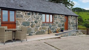 A stone building with a tiled roof, a wooden door, and a window.