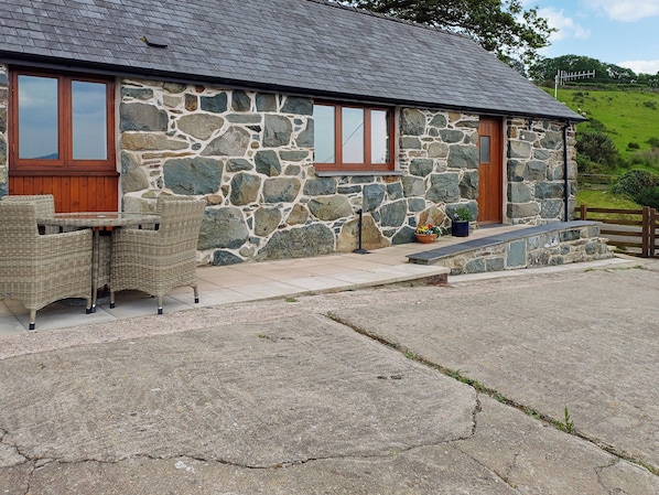 A stone building with a tiled roof, a wooden door, and a window.