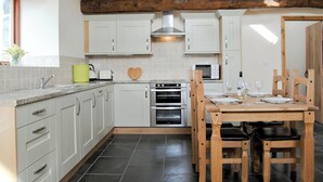 A modern kitchen with white cabinets, a wooden dining table, and a large window.