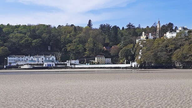 A beach with a row of white buildings and a church with a bell tower.