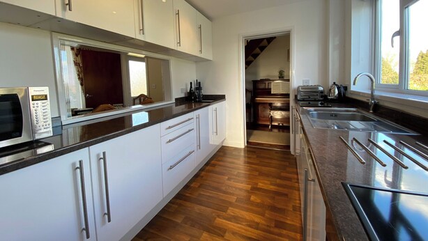 A modern kitchen with white cabinets, a microwave, a sink, and a window providing natural light. - 3 bedroom accommodation in Misterton, near Crewkerne (Misterton, near Crewkerne)
