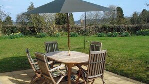 A patio with a round table and four chairs, an umbrella, and a garden in the background. - 3 bedroom accommodation in Misterton, near Crewkerne (Misterton, near Crewkerne)