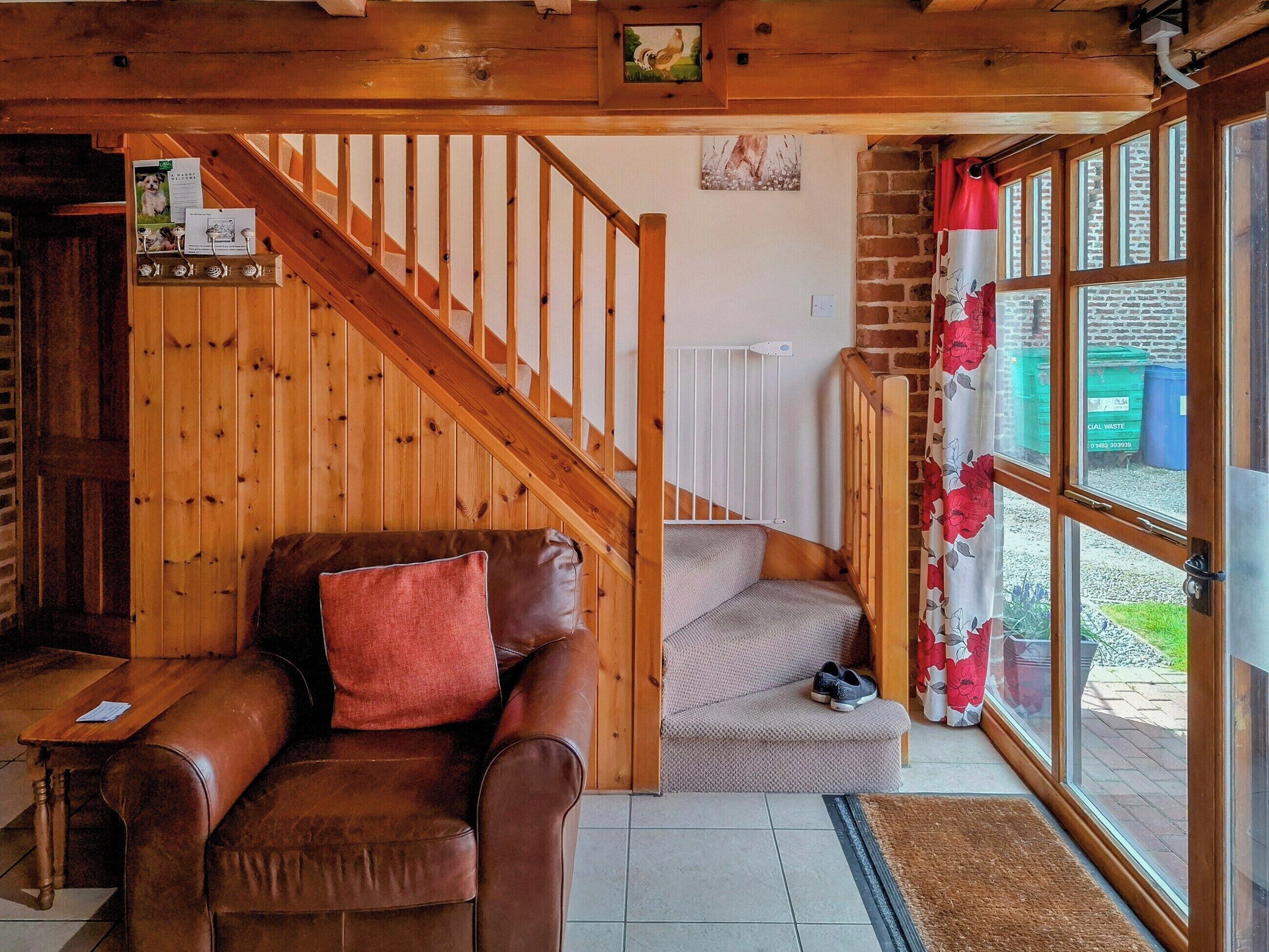 Ein gemütliches Wohnzimmer mit einem braunen Ledersofa, einer grauen Bank und einer Holztreppe.