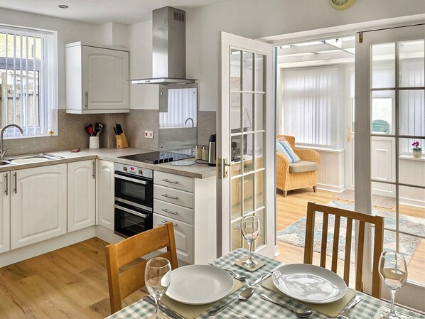 A modern kitchen with white cabinetry, a built-in oven, and a dining area with a table set for two.